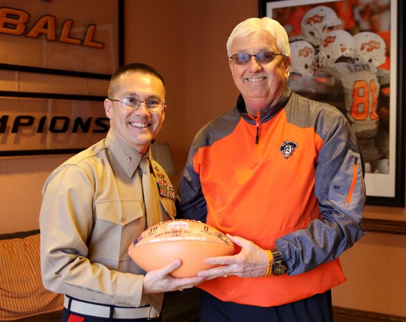 U.S. Marine Corps Director of Intelligence, Brig. Gen. William H. Seely III, poses with Mack Butler, director of football operations at Oklahoma State University, after being presented with a football, Feb 15. Seely visited OSU to speak to Marine Corps officer candidates and deliver a motivational speech to the wrestling team ahead of their National Championship Sunday.