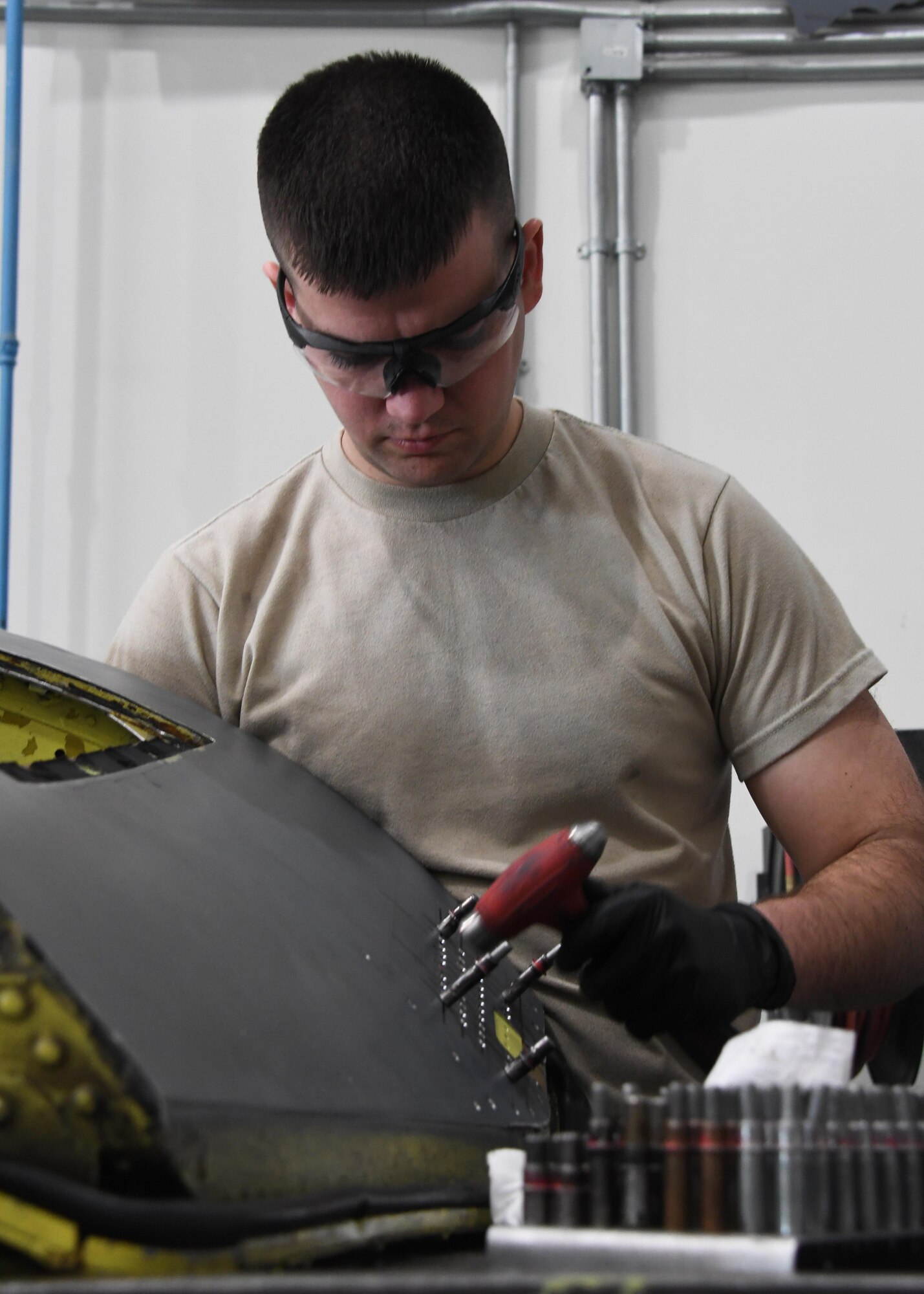 U.S. Air Force Airman 1st Class Stephen Hunter, an aircraft structural maintenance journeyman with the 379th Expeditionary Maintenance Squadron Sheet Metal Shop, prepares to shoot rivets into a boom operator sight at Al Udeid Air Base, Qatar, Feb. 16, 2017. Hunter was installing a patch onto the piece, which fits onto a KC-135 Stratotanker. (U.S. Air Force photo by Senior Airman Miles Wilson)