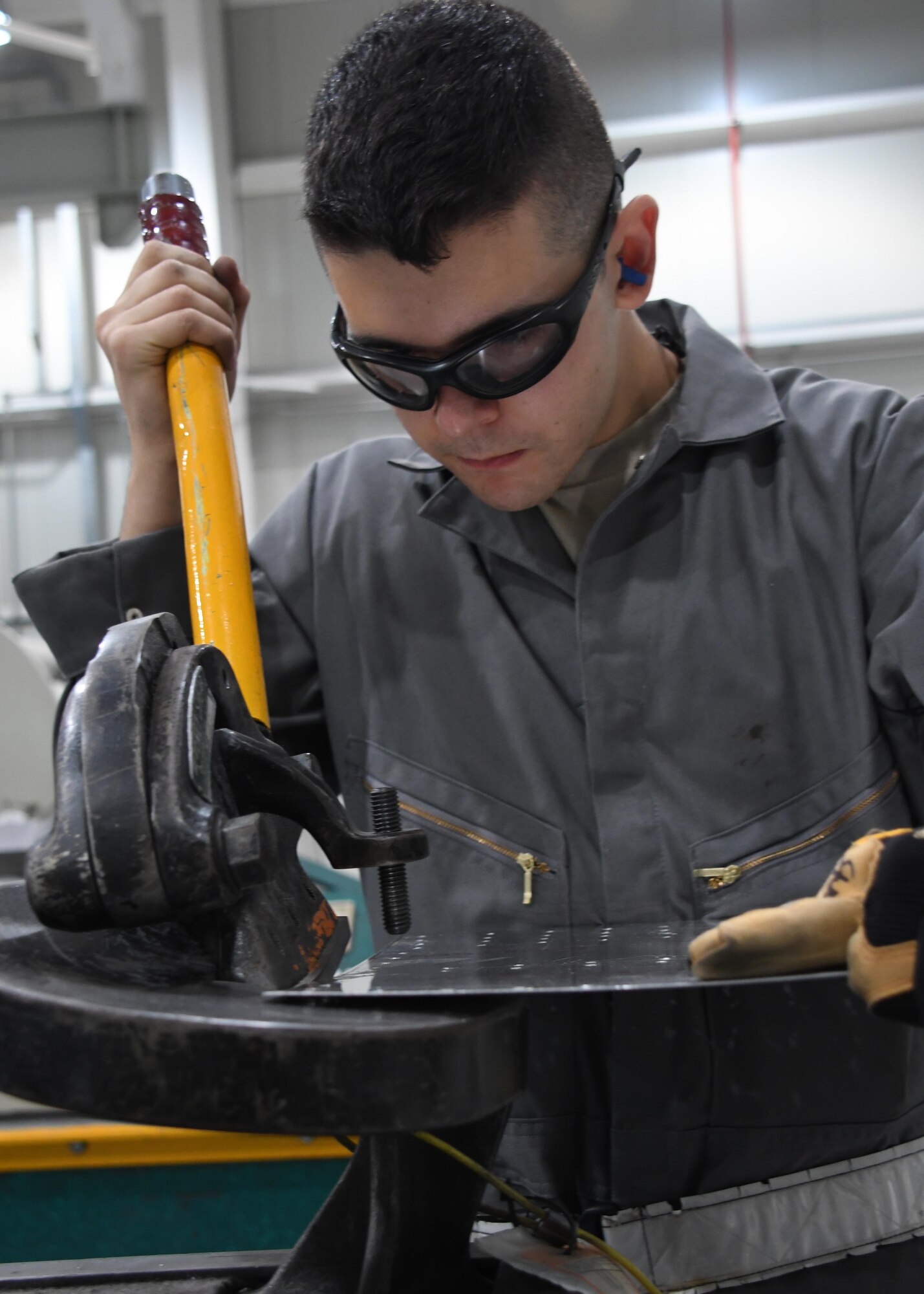 U.S. Air Force Senior Airman Wolfgang Kimsey, an aircraft structural maintenance journeyman with the 379th Expeditionary Maintenance Squadron Sheet Metal Shop, cuts a piece of metal using a throatless shear at Al Udeid Air Base, Qatar, Feb. 16, 2017. Kimsey needed to cut the metal to specific measurements to fit it into place on an outbound flap for an aircraft that lost a piece of metal during flight. (U.S. Air Force photo by Senior Airman Miles Wilson)