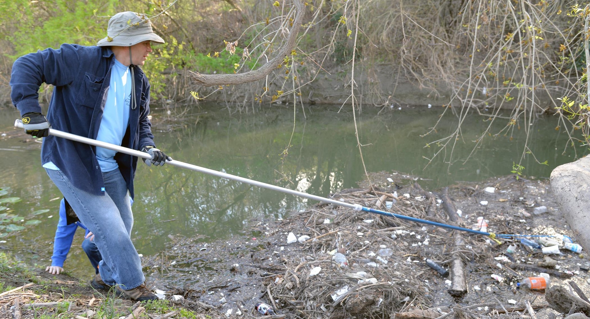 Col. Dave Abraham from U.S. Army South reaches to extract debris from Salado Creek at Joint Base San Antonio-Fort Sam Houston Feb. 17 during the 2017 Basura Bash.