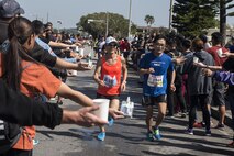 American volunteers hand out water and snacks to Okinawa Marathon runners as they make their way through the base portion of the race Feb. 19, 2017, at Kadena Air Base, Japan. Approximately 500 military volunteers from all branches came out to hand out water and support the runners. (U.S. Air Force photo by Airman 1st Class Corey Pettis/Released)