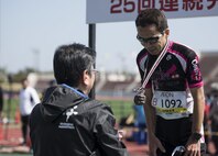 Masanao Ishihara, Okinawan veteran marathoner, receives a commemorative medal, during the 25th annual Okinawa Marathon Feb. 19, 2017, at the Okinawa Prefectural Comprehensive Park in Okinawa, Japan. Commemorative medals were given out to participants who raced and completed the marathon. (U.S. Air Force photo by Senior Airman Omari Bernard/Released)