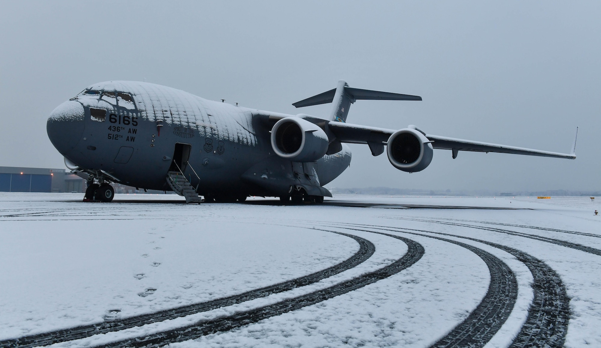 A C-17 Globemaster III is covered in snow in Cologne, Germany, Feb 11, 2017. A 721st Aircraft Maintenance Squadron maintenance recovery team was sent from Ramstein Air Base to fix a number four main fuel tank leak on the aircraft. The leak dripped fuel behind the number four engine exhaust, preventing the crew from flying until it was fixed. (U.S Air Force photo by Senior Airman Tryphena Mayhugh)