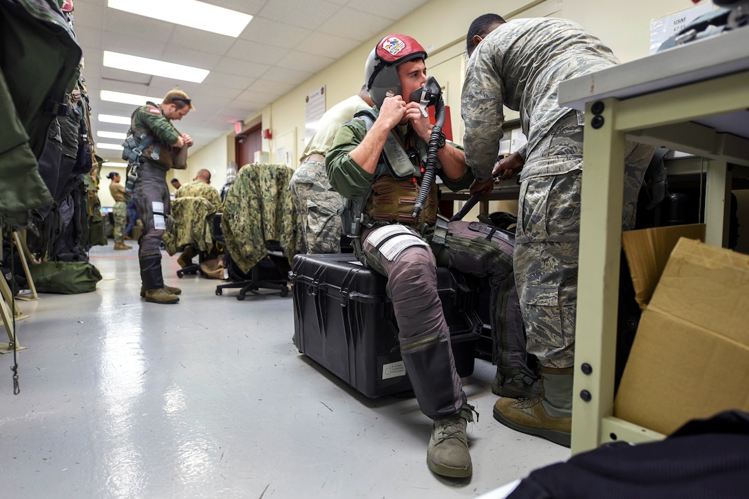 Air Force Capt. Lance Coldren, second right, tests an oxygen mask with an aircrew flight equipment technician during Exercise Cope North at Andersen Air Force Base, Guam, Feb. 20, 2017. Coldren is a pilot assigned to the 67th Fighter Squadron. Flight equipment aircrew conduct a series of tests and checks on equipment before every mission, to include checking the airflow of masks, oxygen levels and ensuring headsets are working properly. Air Force photo by Senior Airman John Linzmeier