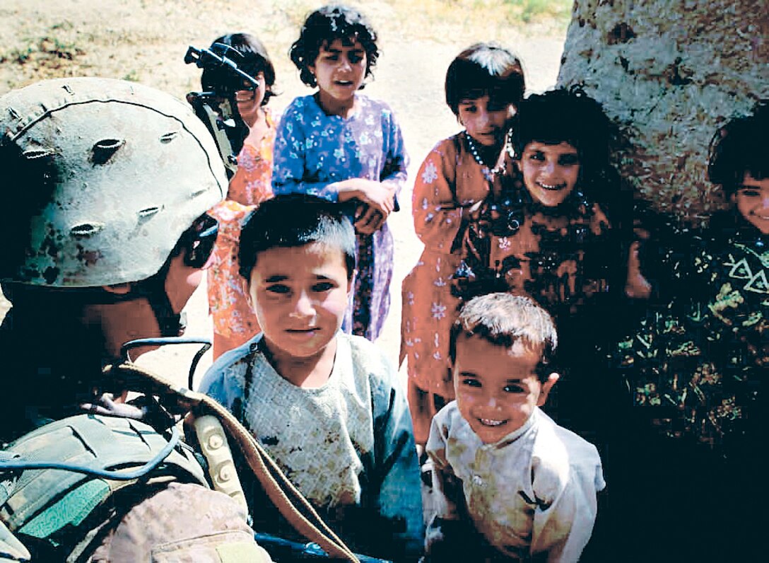 A Marine interacts with children overseas. Likely, his success in another culture can be attributed to Marine Corp Univiserity's CAOCL program.