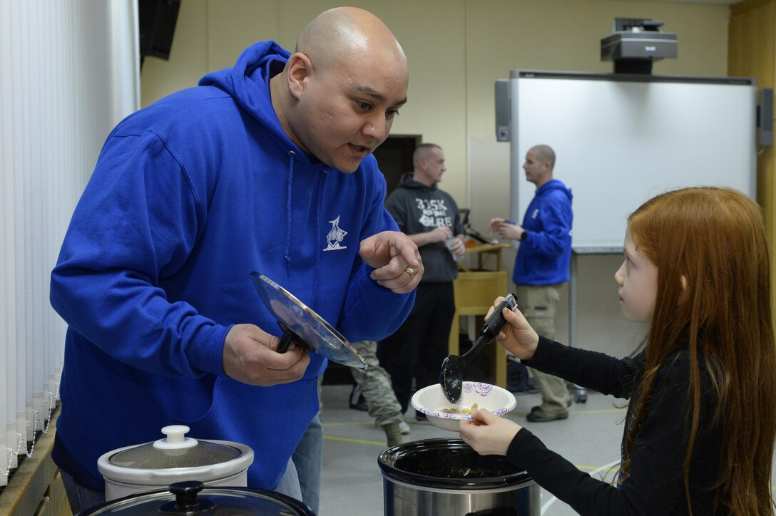 Master Sgt. Benjamin Hill, 52nd Fighter Wing Staff Agencies first sergeant, talks with Liberty Cushing, daughter of deployed Tech. Sgt. Ryan Cushing, as she gets chili during a chili cook-off sponsored by the First Sergeants Association for deployed family night at Spangdahlem Air Base, Germany, Feb. 16, 2017. The Airman and Family Readiness Center holds a deployed family night monthly and different agencies and squadrons take turns sponsoring. (U.S. Air Force photo by Tech. Sgt. Staci Miller)