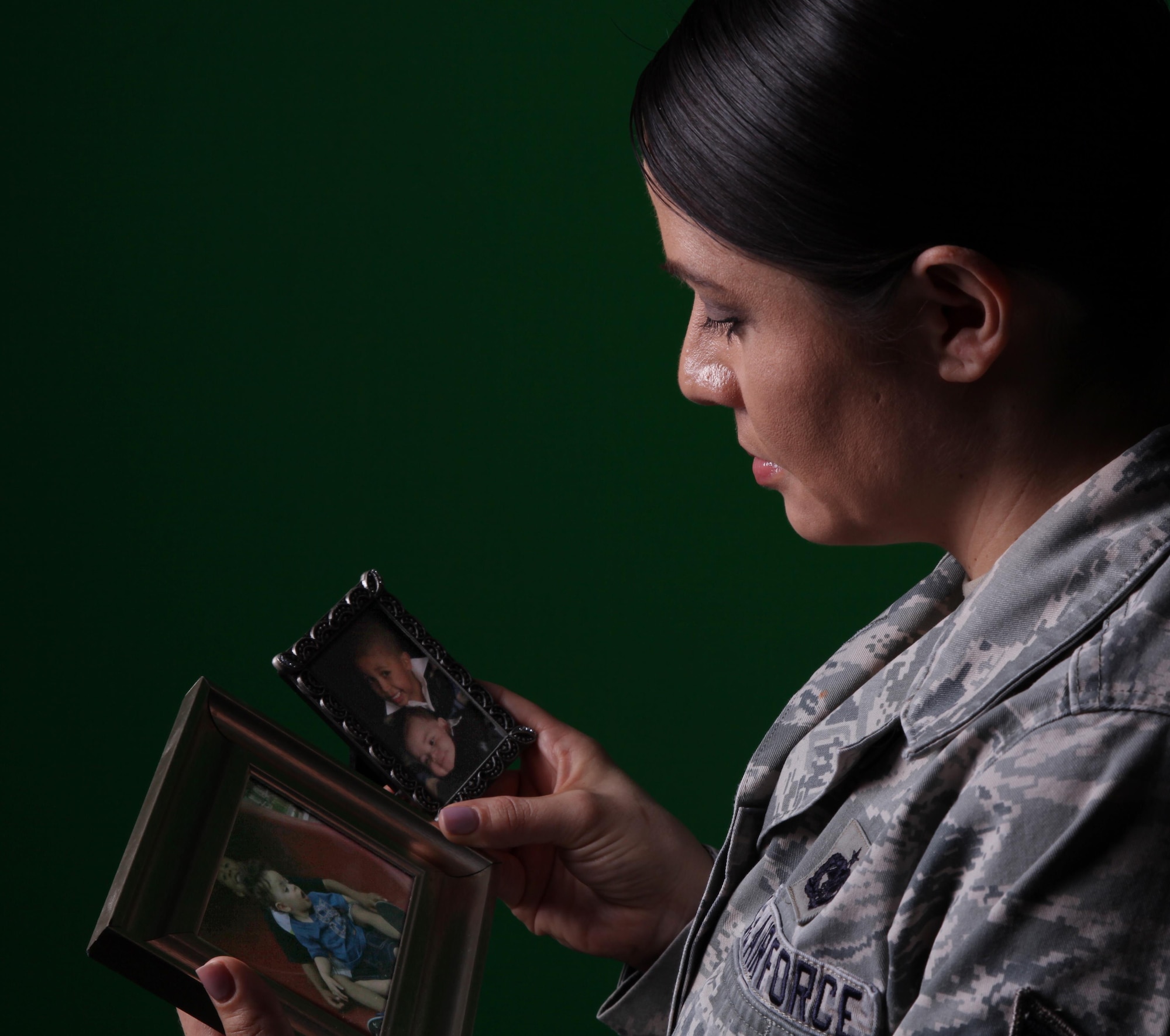 Tech. Sgt. Amee Espinoza, Personnel Customer Service Manager for the ARPC Total Force Service Center, looks at photos of her sons. Espinoza lost her youngest son, but turned the tragedy into therapy and found her calling to serve others through counseling. She completed more than 600 hours of direct and indirect counseling services with individuals and groups focused on DUI and DWIs, addiction, domestic violence, conflict resolution, and anger management and was chosen as the Air Force Reserve Command nomination for the 2016 GEICO Military Service Award. (U.S. Air Force photo by Quinn Jacobson)