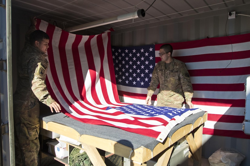 Spc. Brian Ramirez, (left), and Spc. Jose Perez, (right), both mortuary affairs specialists with the 246th Quartermaster Company (Mortuary Affairs), an U.S. Army Reserve unit based out of Mayaguez, Puerto Rico, drapes an American Flag over a transfer case in Erbil, Iraq on February 3, 2017. 