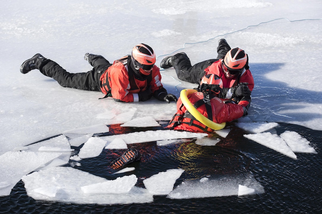 A member of the U.S. Coast Guard, left, observes as Air Force Maj. Gen. Steven Cray, top right, adjutant general, Vermont National Guard, pulls a simulated cold water victim from Lake Champlain during ice water rescue training at Coast Guard Station Burlington, Vt., Feb. 17, 2017. The guardsmen are assigned to an ice rescue team. Cray had the opportunity to work with the Coast Guardsmen as they participated in training using varied techniques designed to rescue people who have fallen through the ice. Air National Guard photo by Tech. Sgt. Sarah Mattison