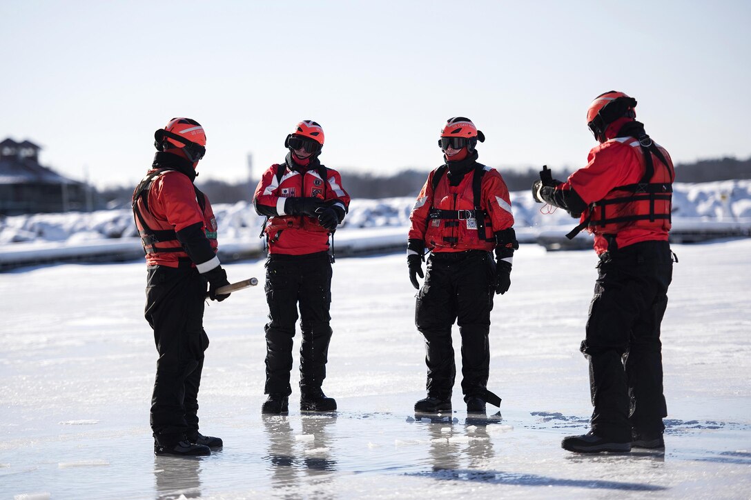 Coast Guard Rear Adm. Steven Poulin, center left, commander, First Coast Guard District, is briefed by Coast Guardsmen on Lake Champlain during ice water rescue training at Coast Guard Station Burlington, Vt., Feb. 17, 2017. Air National Guard photo by Tech. Sgt. Sarah Mattison