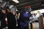 After tracing her initials onto the keel plate of DDG 121 -- the future USS FRANK E. PETERSEN, JR. -- Mrs. D'Arcy Neller, authenticator and ship sponsor, watches from behind a protective mask as Ingalls Shipbuilding structural welder Jeremy Lally etches her initials into the ship's keel plate.  The keel authentication ceremony for DDG 121 was held Tuesday morning, Feb. 21, at Ingalls Shipyard in Pascagoula, MS.  Also observing at left is Ingalls Shipbuilding President Mr. Brian Cuccias.  The keel's co-authenticator, Mr. Donald Brabston, a 50-year Ingalls employee, was unable to attend.  