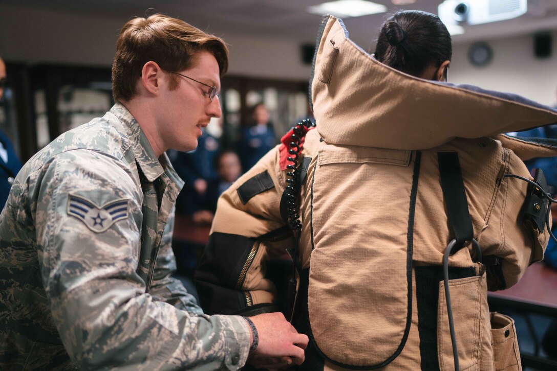 Senior Airman Joshua Holbrook, 11th Civil Engineer Squadron explosive ordinance disposal technician, helps a Baltimore Polytechnic Institute High School Air Force Junior Reserve Officer Training Corps cadet try on EOD protective gear at Joint Base Andrews, Md., Feb. 16, 2017. The visit worked to acquaint cadets with specific duties performed by Airmen and to assist them in selecting a specific career field. (U.S. Air Force photo by Senior Airman Delano Scott) 