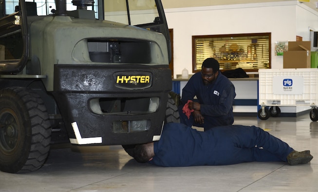 Walter Wilson and U.S. Air Force Airman 1st Class Nicholas Imber, 733rd Logistics Readiness Squadron vehicle maintainers, use a grease gun to squeeze bio-based grease into a forklift carriage at Joint Base Langley-Eustis, Va., Jan. 31, 2017. JBLE is one of four Air Force bases that will perform a 12-month long test of the grease on its vehicles. (U.S. Air Force photo by Airman 1st Class Kaylee Dubois)