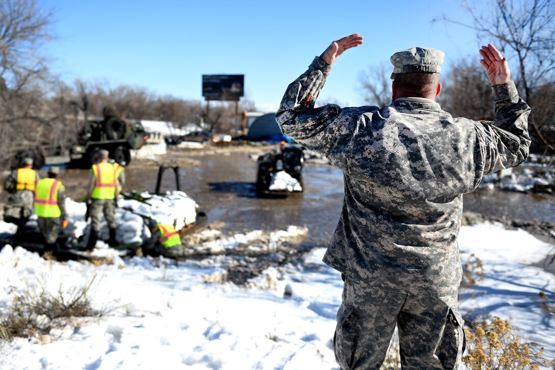 An Army National Guard soldier directs a forklift transporting pallets of sandbags to reinforce berms along the Bighorn River in Worland, Wyo., Feb. 12, 2017. Army National Guard photo by Sgt. 1st Class Jimmy McGuire 