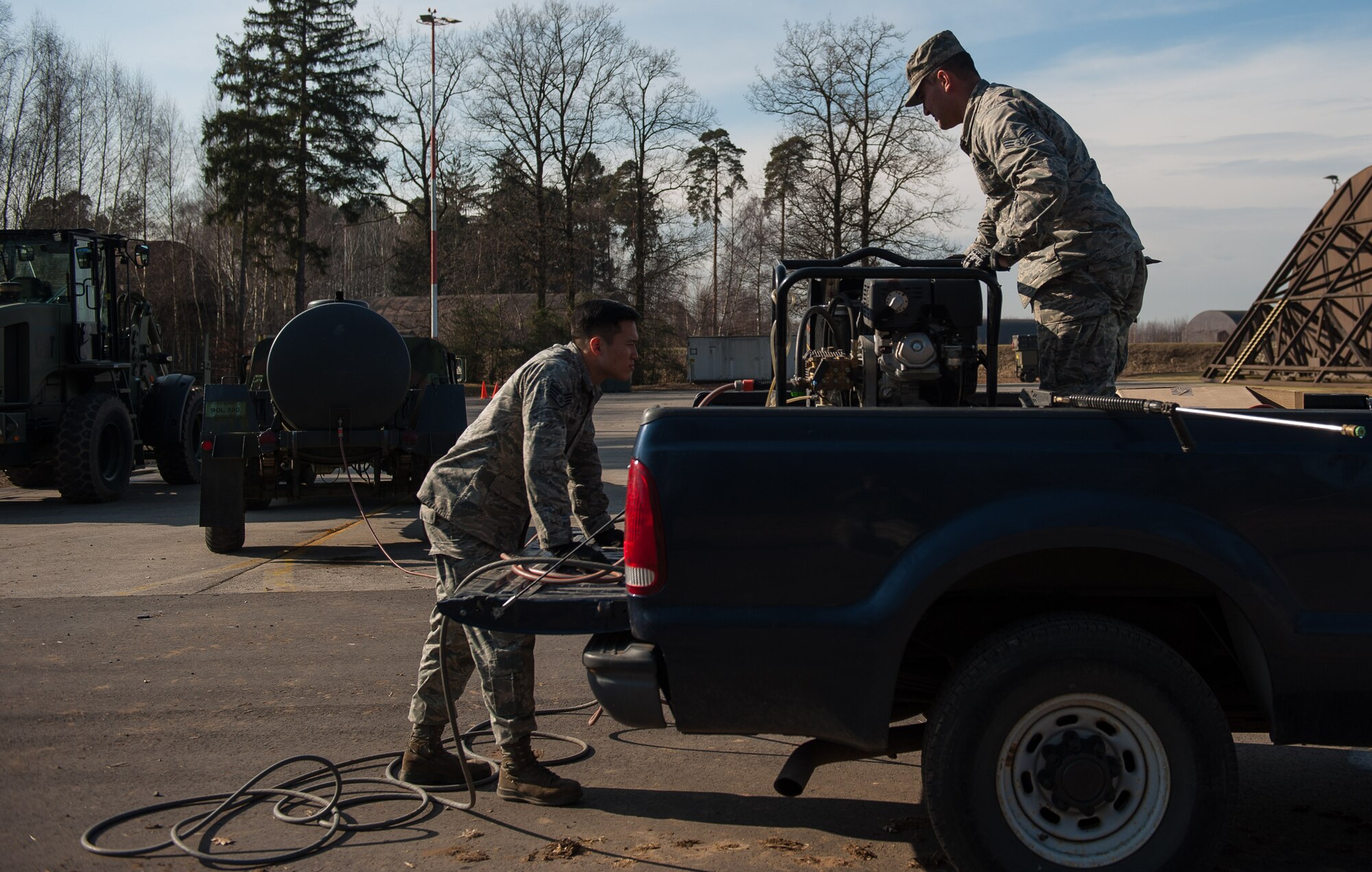 Staff Sgt. Ju Ho Park, 1st Combat Communications Squadron electrical power production craftsman, and Senior Airman Christopher Pakusch, 1 CBCS electrical power production journeyman, lower a water power pressure machine during a mock deployment exercise on Ramstien Air Base, Germany, Feb. 16, 2017. Airmen from 1 CBCS use mock-deployment exercises to enhance job skills and maintain equipment to be prepared for deployments at any given time. (U.S. Air Force photo by Senior Airman Lane T. Plummer)