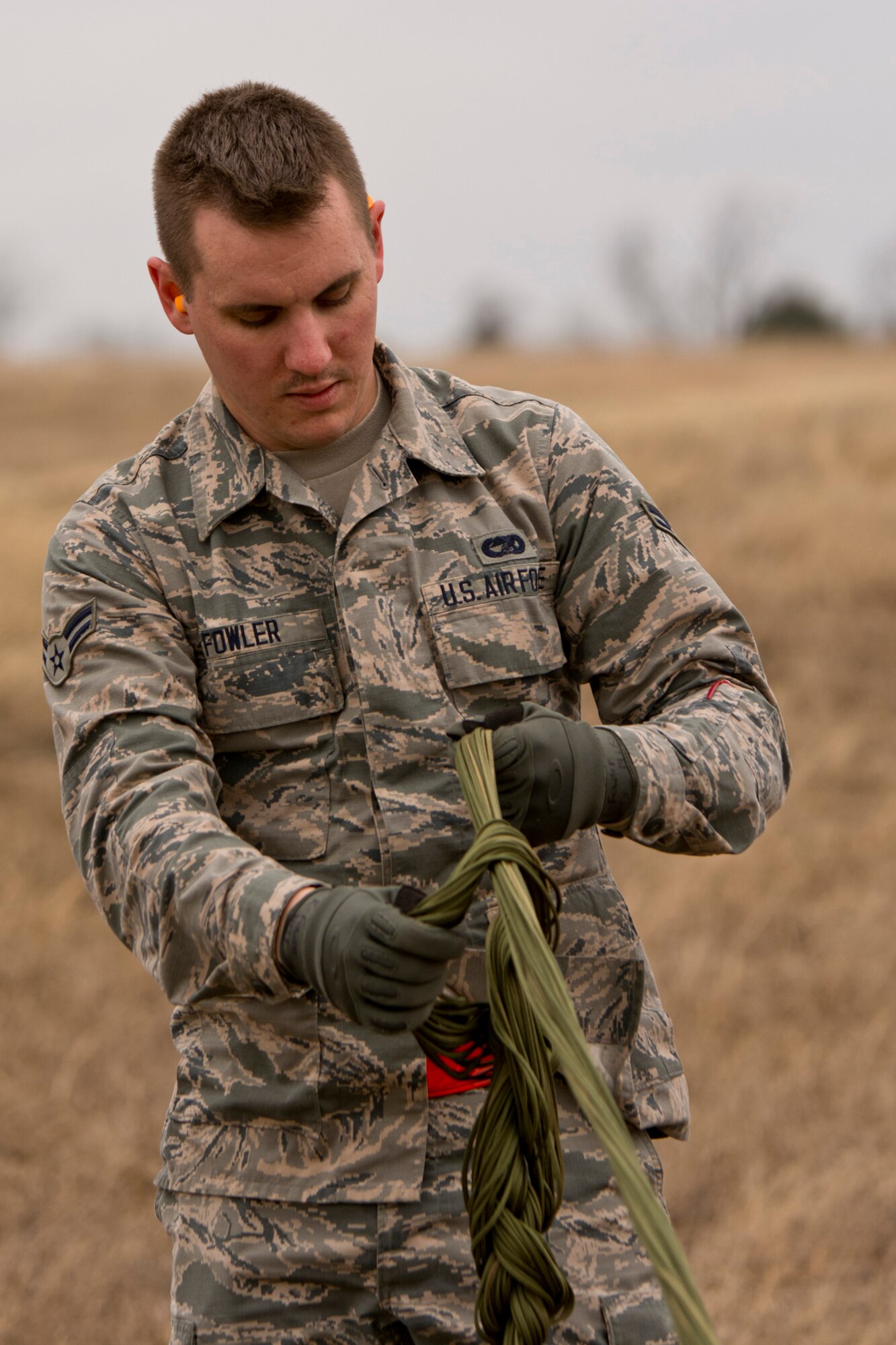 U.S. Air Force Airman 1st Class Kody Fowler, air transportation, 19th Logistics Readiness Squadron, daisy chains suspension lines of a 26-foot G-12 Cargo Parachute Feb. 11, 2017, at Black Jack Drop Zone near Beebe, Ark. This method of recovering parachutes reduces the possibility of lines becoming entangled during recovery operations and parachutes catching air during transportation. (U.S. Air Force photo by Master Sgt. Jeff Walston/Released)