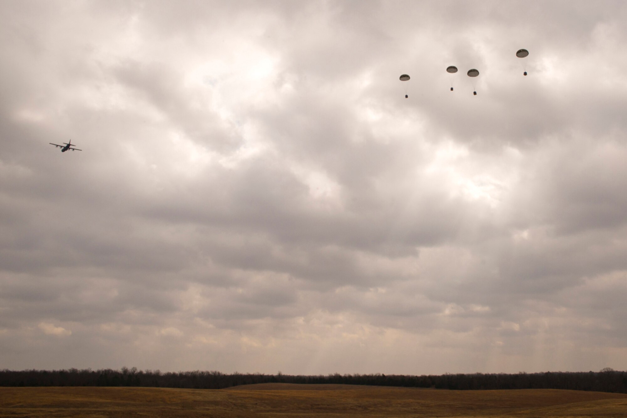 A C-130J Super Hercules drops four water barrel container delivery system (CDS) bundles during a training sortie at Black Jack Drop Zone Feb. 11, 2017, near Beebe, Ark. Airmen from the 327th Airlift Squadron, part of the 913th Airlift Group, practice airdropping CDS bundles to enhance skills used during humanitarian and combat missions. (U.S. Air Force photo by Master Sgt. Jeff Walston/Released)