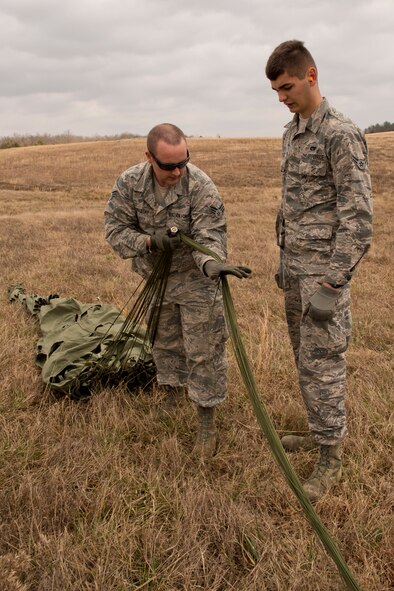 U.S. Air Force Senior Airman Shane Mastay teaches Airman 1st Class Allen Wiltse how to daisy chain the suspension lines of a cargo parachute Feb. 11, 2017, at Black Jack Drop Zone near Beebe, Ark. Both Airmen are assigned to air transportation in the 19th Logistics Readiness Squadron at Little Rock Air Force Base and must be able to use this method to reduce the possibility of lines becoming entangled during recovery operations and transportation. (U.S. Air Force photo by Master Sgt. Jeff Walston/Released)
