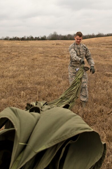 U.S. Air Force Airman Alex Eby, air transportation, 19th Logistics Readiness Squadron, rolls a collapsed 26-foot G-12 Cargo Parachute Feb. 11, 2017, at Black Jack Drop Zone near Beebe, Ark. Rolling parachutes during the recovery process helps remove debris and saves space for storage during transportation. (U.S. Air Force photo by Master Sgt. Jeff Walston/Released)