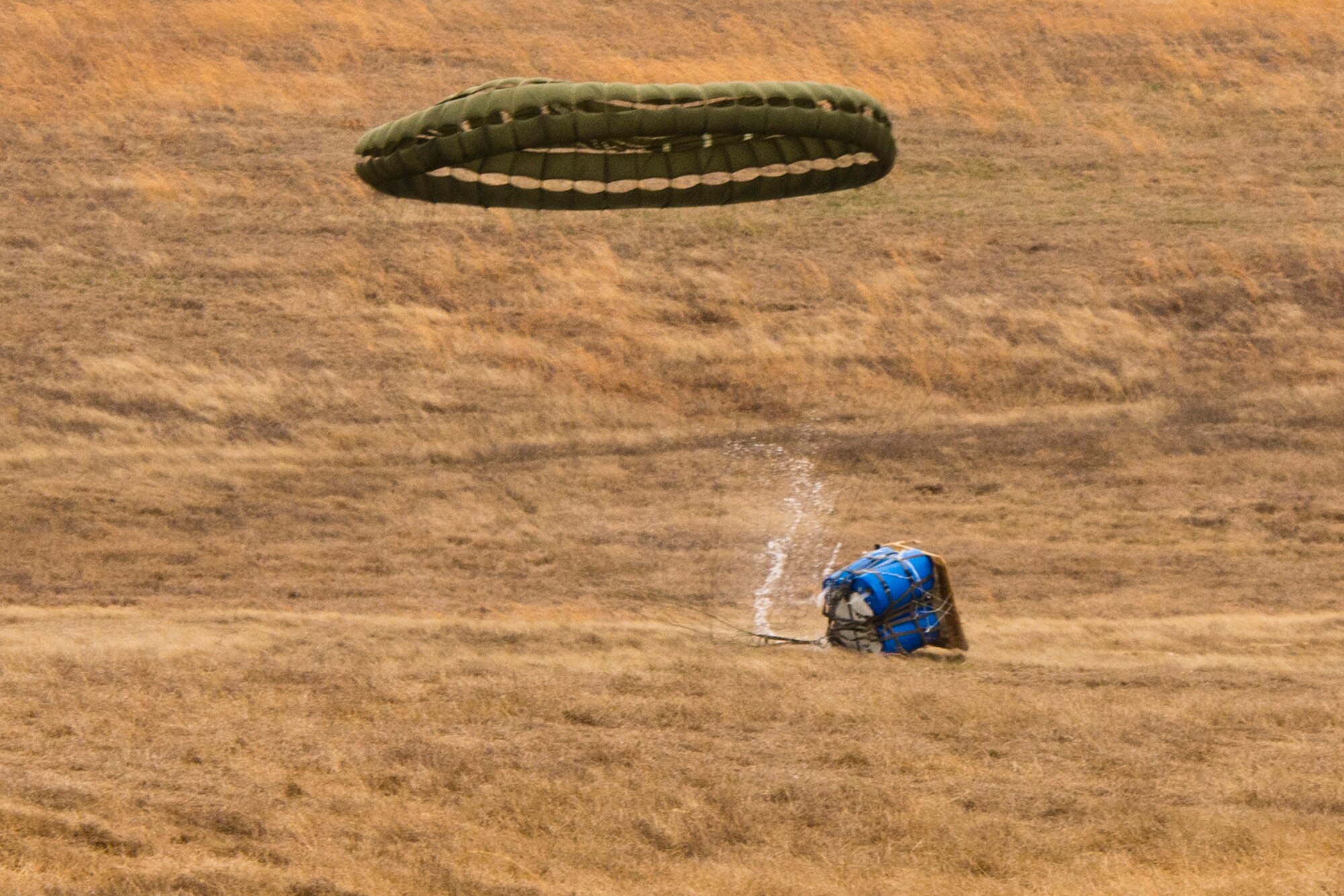 A water barrel container delivery system (CDS) bundle air dropped from a C-130J Super Hercules hits the ground at the Blackjack Drop Zone Feb. 11, 2017, near Beebe, Ark. The water barrel CDS is preferred to the steel cage load because less man power is needed for reconstitution of the CDS, and the cost savings to replace or repair the bundle. (U.S. Air Force photo by Master Sgt. Jeff Walston/Released)