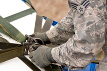 U.S. Air Force Senior Airman Senior Airman Shane Mastay, air transportation, 19th Logistics Readiness Squadron, disconnects a parachute from an A-22 Cargo Sling on a water barrel container delivery system (CDS) at the Blackjack Drop Zone Feb. 11, 2017, near Beebe, Ark. The CDS is the most commonly used wat to insert cargo and supplies for military operations from the air. (U.S. Air Force photo by Master Sgt. Jeff Walston/Released)