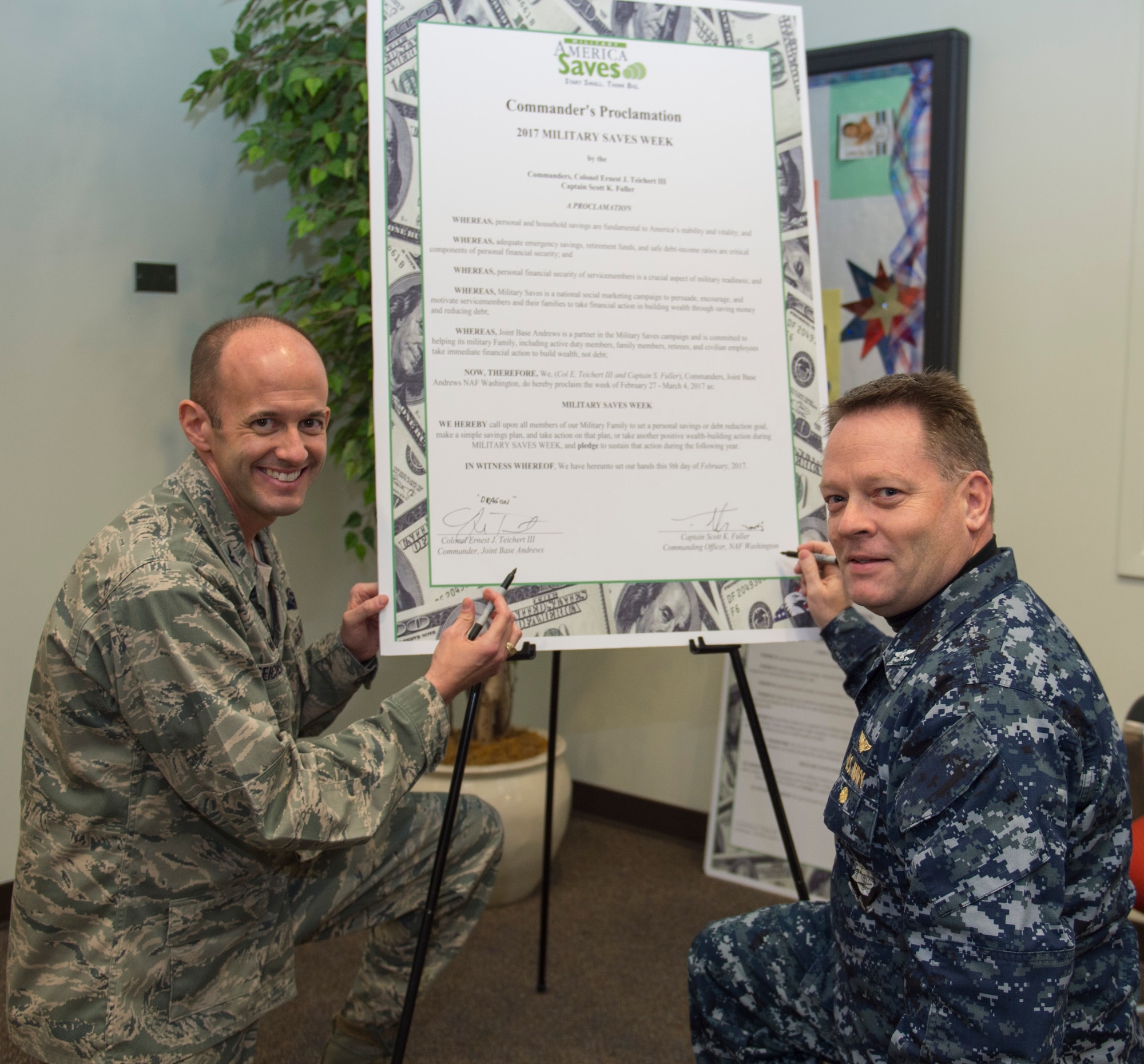 U.S. Air Force Col. E. John Teichert, 11th Wing and Joint Base Andrews commander, left, and U.S. Navy Capt. Scott Fuller, Naval Air Station Washington commanding officer, right, pose for a photo after signing the Military Saves Week proclamation at JBA, Md., Feb. 9, 2017. Military Saves Week will take place from Feb. 27 to March 3. (U.S. Air Force photo by Senior Airman Dylan Nuckolls)