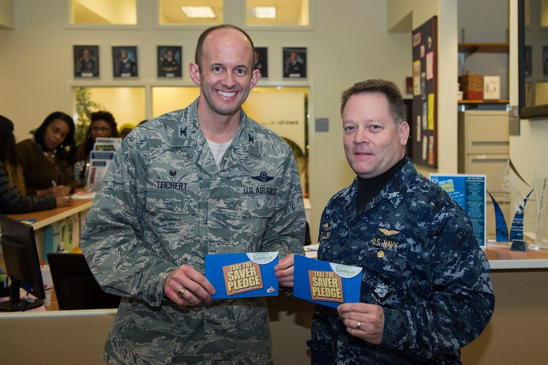 U.S. Air Force Col. E. John Teichert, 11th Wing and Joint Base Andrews commander, left, and U.S. Navy Capt. Scott Fuller, Naval Air Station Washington commanding officer, right, pose for a photo during the Military Saves Week proclamation signing at JBA, Md., Feb. 9, 2017. Military Saves Week will take place from Feb. 27 to March 3 and will feature public briefings, in-unit workshops tailored to individual offices, and financial information booths. (U.S. Air Force photo by Senior Airman Dylan Nuckolls) 