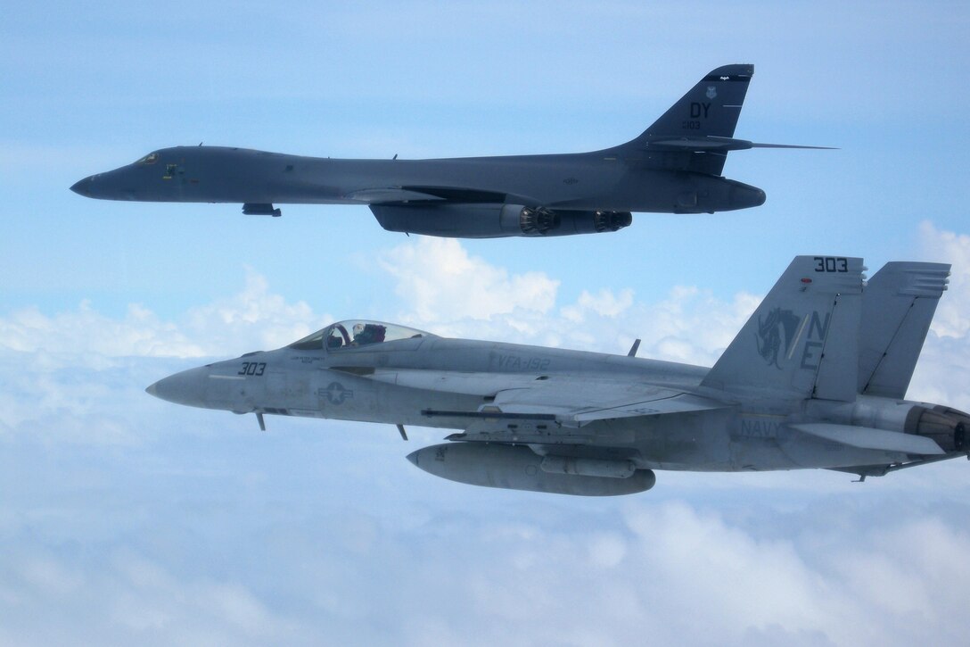 A B-1B Lancer Bomber and an F/A-18E Super Hornet fly over the aircraft carrier USS Carl Vinson as it transits the Philippine Sea, Feb. 14, 2017. The Hornet pilots are assigned to Strike Squadron 192. Navy photo by Lt. Robert Nordlund