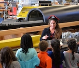Jennifer Brewster, the events lead from Naval Surface Warfare Center, Carderock Division in West Bethesda, Md., Oct. 31, 2016, shows a group of students from Lucy V. Barnsley Elementary School a ship model in the Woodworking Shop at Carderock during a science, technology, engineering and math (STEM) event.
