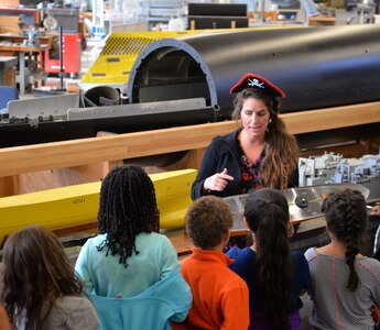 Jennifer Brewster, the events lead from Naval Surface Warfare Center, Carderock Division in West Bethesda, Md., Oct. 31, 2016, shows a group of students from Lucy V. Barnsley Elementary School a ship model in the Woodworking Shop at Carderock during a science, technology, engineering and math (STEM) event.