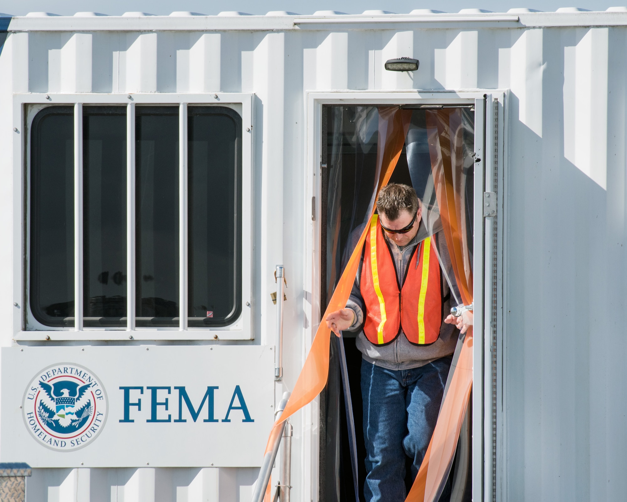 A Federal Emergency Management Agency representative exits the Logistics Mobile Office C2 Unit at Travis Air Force Base, Calif., Feb. 16, 2017. Travis AFB is acting as a staging area for FEMA personnel, providing space for necessary equipment and supplies in case of the Oroville auxiliary spillway failure. (U.S. Air Force photo/Louis Briscese)