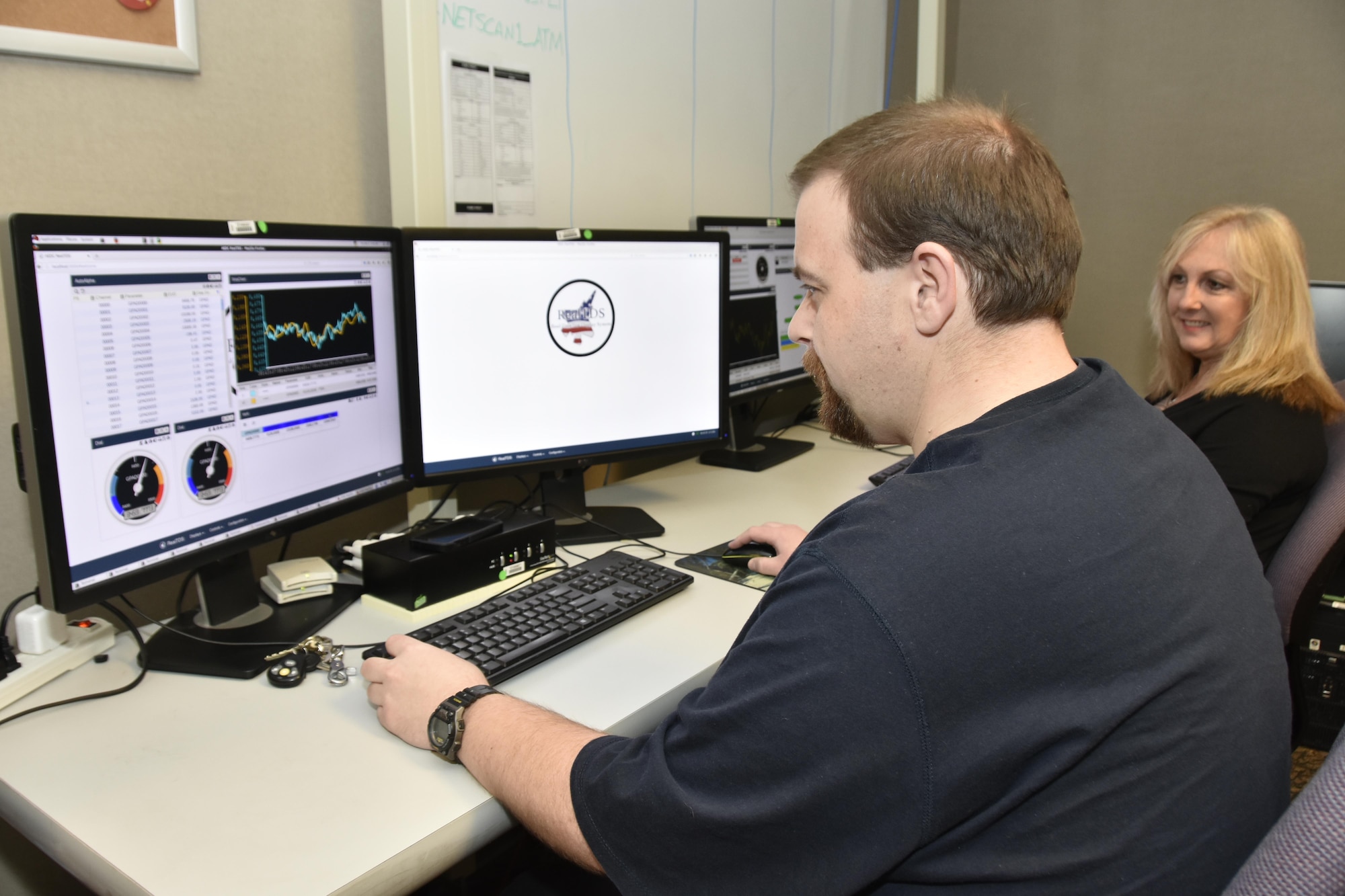 Chad Dotson, software engineer for the Real-Time Test Display System team at AEDC, works with the RealTDS software, which enables the test engineers and test customers to view data in real time. Looking on at right is Danna Pemberton, software engineer. (U.S. Air Force photo/Rick Goodfriend)