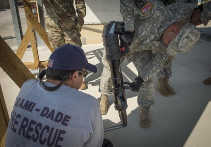 Lt. Chris Pecori, Miami-Dade Fire Rescue air rescue training officer, observes U.S. Army Reserve Spc. Luis Colon, 329th Chemical Company chemical biological warfare specialist, operate rescue and containment equipment during hazardous material training on Miami-Dade Fire Rescue headquarters, Miami, Fl. Feb 17, 2016. These training events were held by fire rescue personnel in preparation for a validation exercise held by U.S. Army North and U.S. Northern Command. 