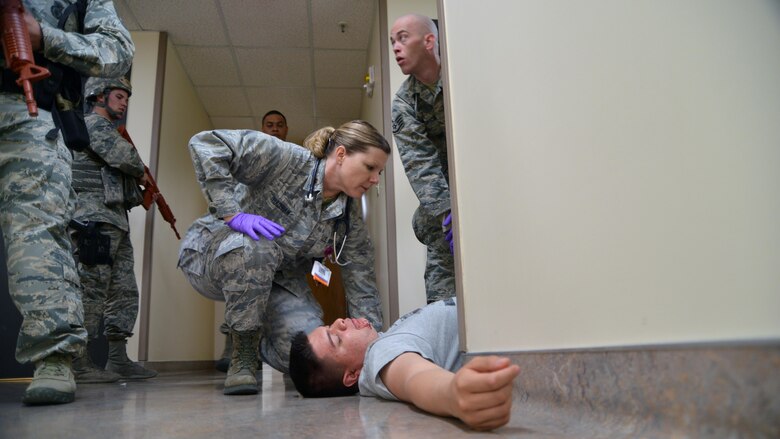 Major Allison Bradshaw, 377 Aerospace Medicine Squadron operational medicine flight commander, tends to a patient while under security forces escort during an active shooter exercise at the 377 Medical Group clinic Feb. 21. Because of the nature of the exercise, medics had to triage the patients before rendering medical care. (U.S. Air Force Photo/Senior Airman Chandler Baker) 