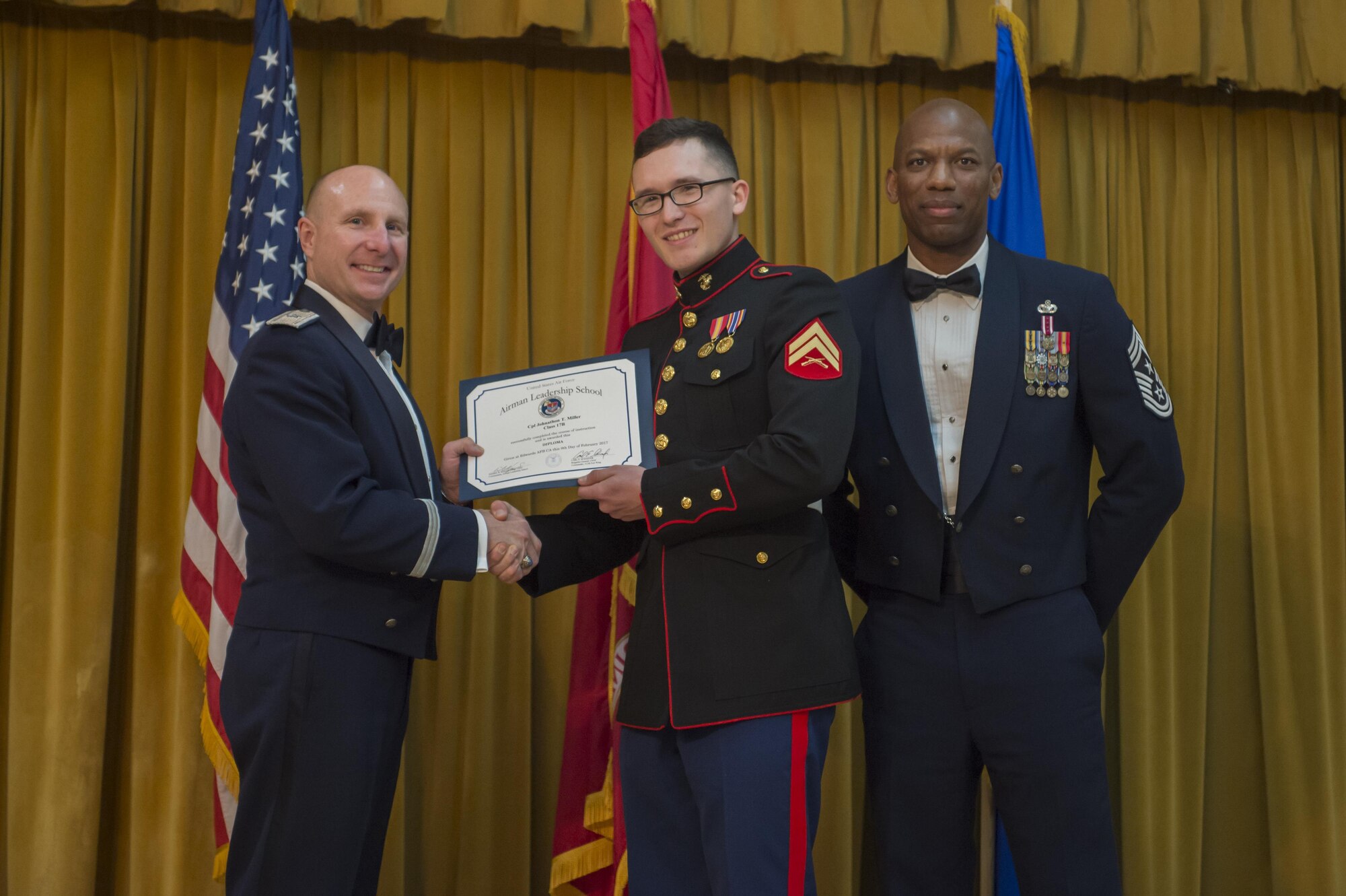 From left: Brig. Gen. Carl Schaefer, 412th Test Wing commander, presents an Airman Leadership School graduation certificate to Cpl. Johnathan Miller, U.S. Marine Corps VMX-22, along with Chief Master Sgt. Todd Simmons, 412th TW command chief. Miller also won the John L. Levitow Award for ALS Class 17B, which graduated Feb. 9. The Levitow award is presented to the student that demonstrated the most outstanding leadership and scholastic qualities. (U.S. Air Force photo by Kyle Larson)