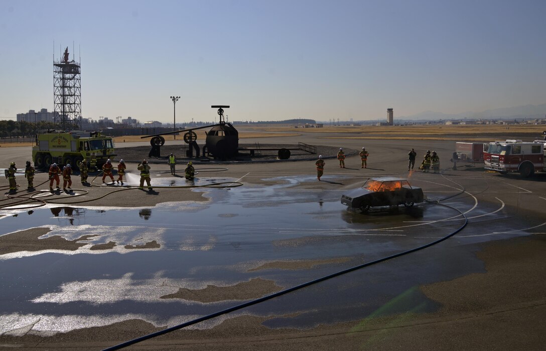 Fire fighters from the Japan Self-Defense Force and 374th Civil Engineer Squadron Fire Departments prepare to complete a vehicle fire training scenario at Yokota Air Base, Japan, Feb. 16, 2017. During the training the firefighters were split into three teams of two, with two teams extinguishing the fires and the remaining team on standby providing a safety line to help the primary teams. (U.S. Air Force photo by Staff Sgt. David Owsianka)