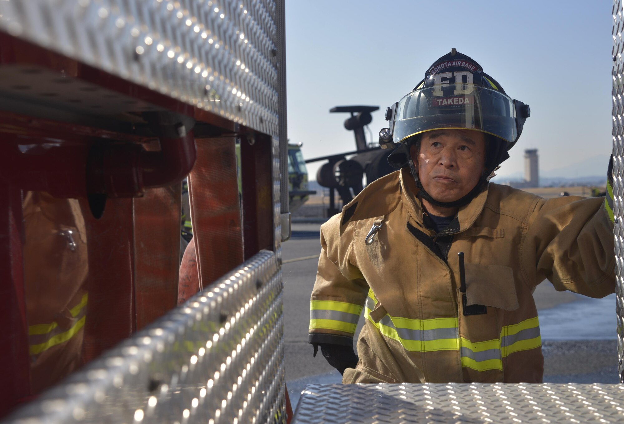 Nobuhito Takeda, 374th Civil Engineer Squadron Fire Department fire fighter, climbs up a fire truck to help unload a hose prior to completing a vehicle fire training scenario at Yokota Air Base, Japan, Feb. 16, 2017. Yokota’s personnel trained with the Japan Self-Defense Force and Fussa fire departments to gain different perspectives on putting out vehicle fires. (U.S. Air Force photo by Staff Sgt. David Owsianka)