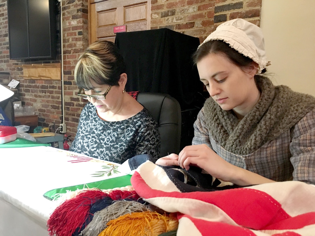 DLA Troop Support flag room embroider Nereida Rivera, left, stitches a vice presidential flag alongside a Betsy Ross interpreter during a museum exhibit opening at the Betsy Ross House Feb. 17 in Philadelphia.  Rivera is one of 16 DLA embroiders featured in “Historic Threads: 250 Years of Flag Making in Philadelphia,” which highlights the city’s centuries-long tradition of flag making. 
