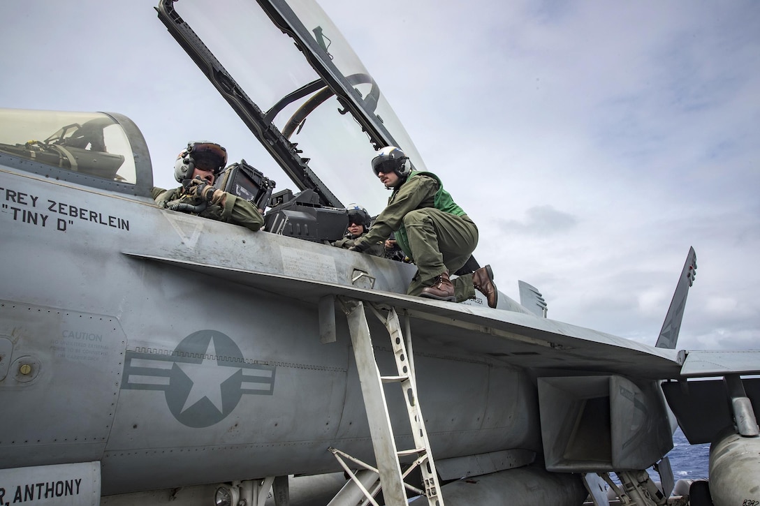 A sailor prepares the pilots inside the cockpit of an FA-18F Super Hornet before takeoff on the flight deck of the aircraft carrier USS Carl Vinson in the Philippine Sea, Feb. 15, 2017. The sailor is an aviation ordnanceman assigned to Strike Fighter Squadron 2. Navy photo by Seaman Jake Cannady