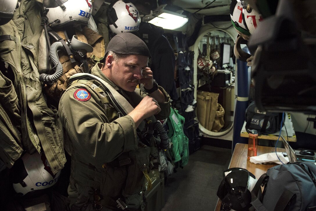 Navy Cmdr. Derek Duford, commander of Strike Fighter Squadron 34, dons his survival flight equipment on the aircraft carrier USS Carl Vinson in the Philippine Sea, Feb. 15, 2017. Navy photo by Petty Officer 3rd Class Matt Brown