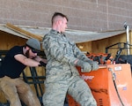 Senior Airman Justin Smith and Mr. Jacob Stahl, 460th Civil Engineering Squadron heavy equipment operators, work to realign machinery used to cut into the cement Feb. 17, 2017 at a dig site on Buckley Air Force Base, Colo. The alignment of the machine is crucial to ensure the lines are straight. (U.S. Air Force photo by Airman 1st Class Jessica A. Huggins/Released)