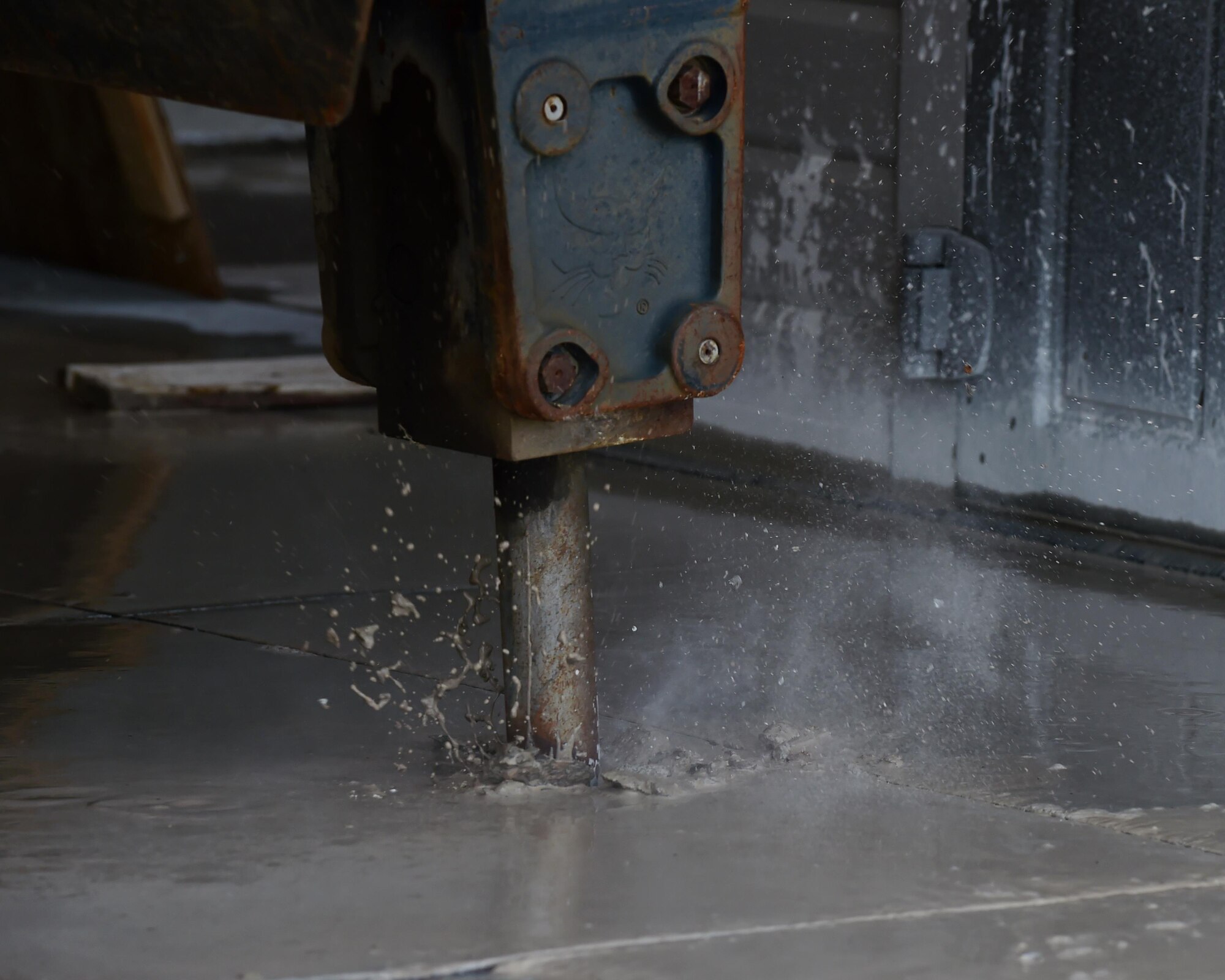 The hydraulic attachment of a Bobcat machine digs a whole into the concrete Feb. 17, 2017 on Buckley Air Force Base, Colo. This is one of the first steps in the process of fixing a pipe leak. (U.S. Air Force photo by Airman 1st Class Jessica A. Huggins/Released)
