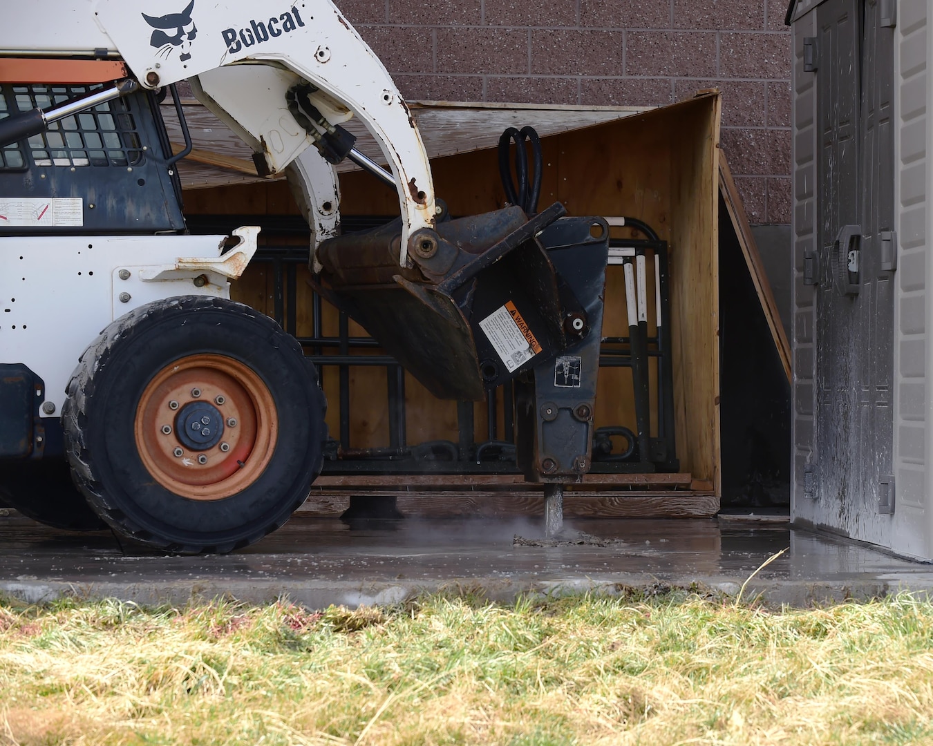 A Bobcat machine with a hydraulic attachment breaks through concrete Feb. 17, 2017 on Buckley Air Force Base, Colo. These machines are operated solely by trained members of the 460th Civil Engineering Squadron. (U.S. Air Force photo by Airman 1st Class Jessica A. Huggins/Released)