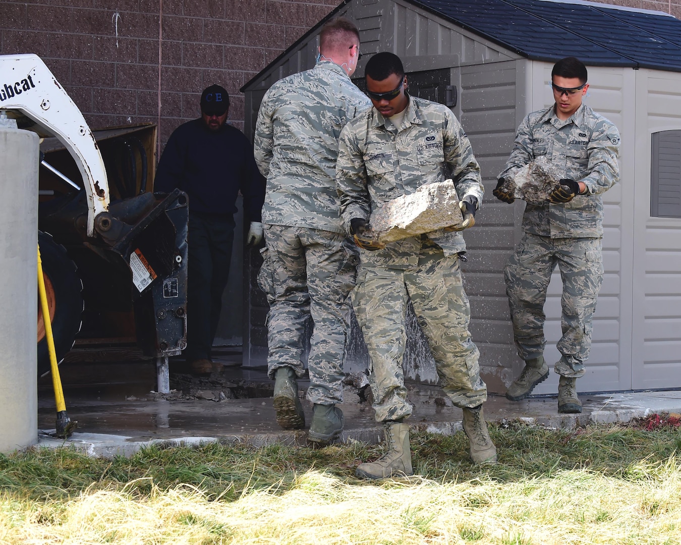 Airman 1st Class Justin Johnson and Airman Gabriel Gonzales, 460th Civil Engineering Squadron heavy equipment operators, remove excess concrete from a dig site Feb. 17, 2017 on Buckley Air Force Base, Colo. Most of the jobs done by CES require a team for safety and efficiency. (U.S. Air Force photo by Airman 1st Class Jessica A. Huggins/Released)