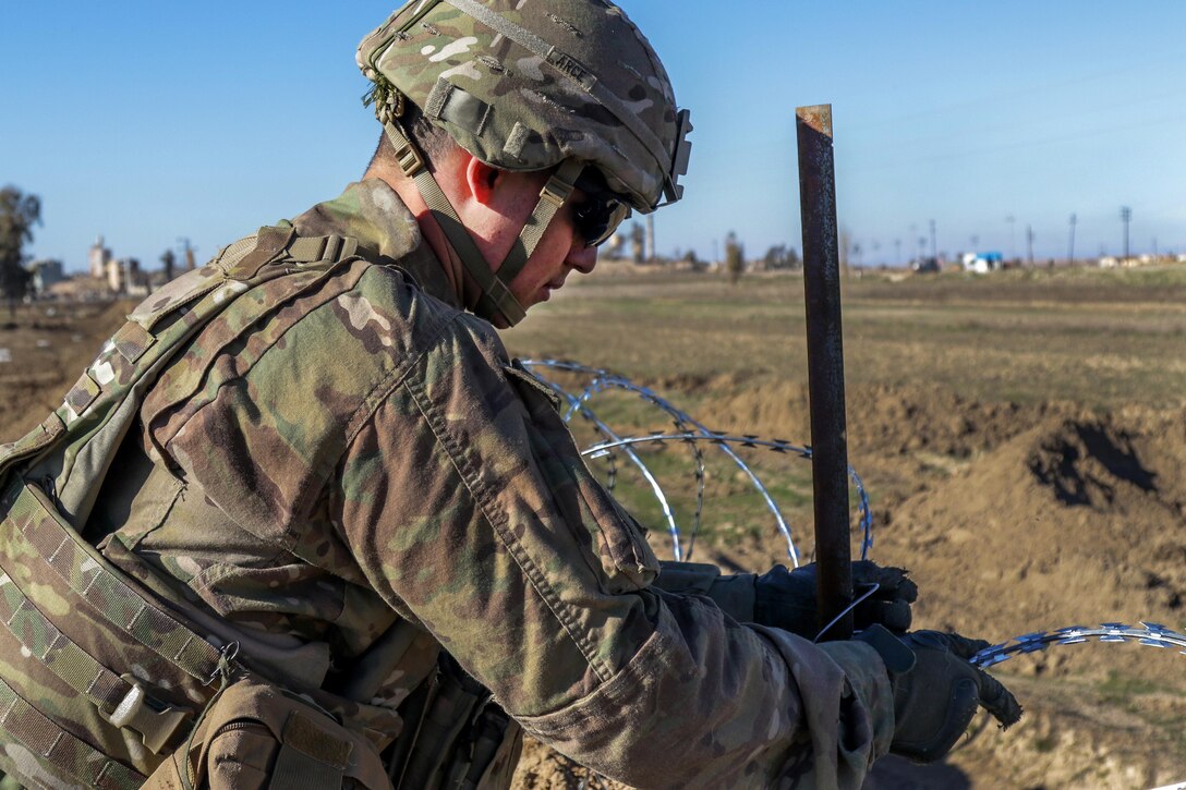 Army Spc. Emmanuel Arce reinforces the perimeter security by emplacing concertina wire at Hamam al-Alil, Iraq, Feb. 18, 2017. Arce is a combat engineer assigned to the 82nd Airborne Division’s 37th Brigade Engineer Battalion, 2nd Brigade Combat Team. Army photo by Staff Sgt. Jason Hull 