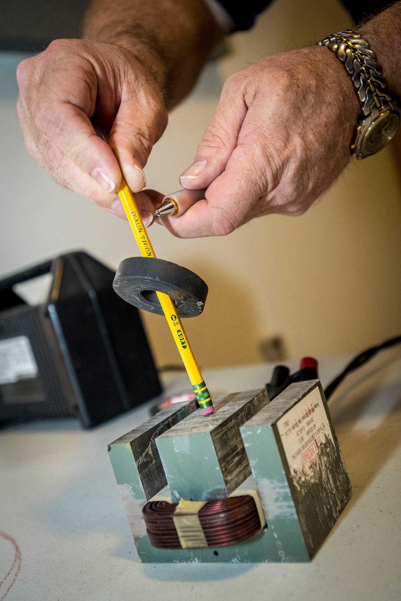 Paul Stout, 516th Software Maintenance Squadron electronics engineer, levitates a 3.7-ounce magnet using a functional magnetic levitation system Feb. 23 at the Hill Aerospace Museum. Stout, along with other professional engineers, participated in Levitate! as part of National Engineers Week. The magnet levitated nearly 4 inches high on the pencil.  (U.S. Air Force photo by Paul Holcomb)