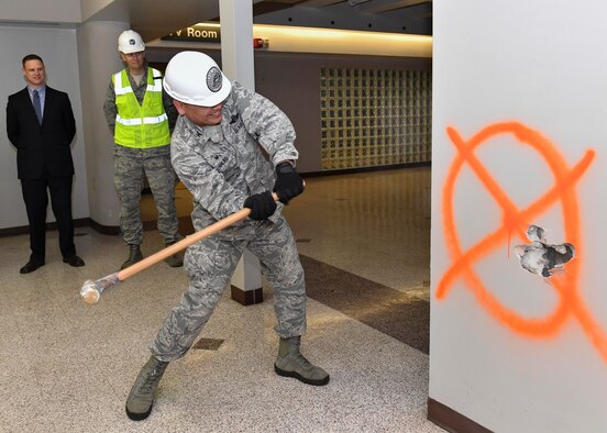 Col. Jimmy Canlas, 437th Airlift Wing commander, swings a sledgehammer to start construction of the new 437th Aerial Port Squadron Passenger Terminal here, Feb. 23, 2017. The passenger terminal is being renovated to improve the facility by adding a new fire suppression system, roof, utility systems, restrooms inside the gated area and a redesigned family room. The passenger terminal will operate out of a temporary facility until construction is complete. Signage is in place to direct passengers and base personnel from the old terminal to the temporary location. 