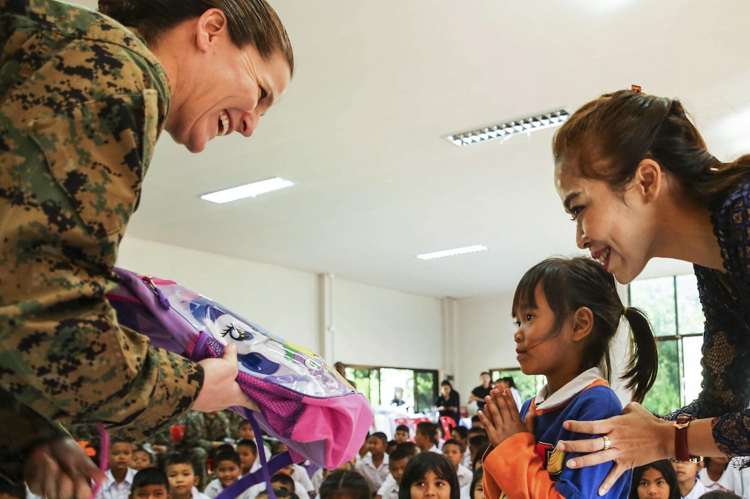 Marine Corps Col. Maria McMillen gives school supplies to a Thai girl at a school in Chanthaburi, Thailand