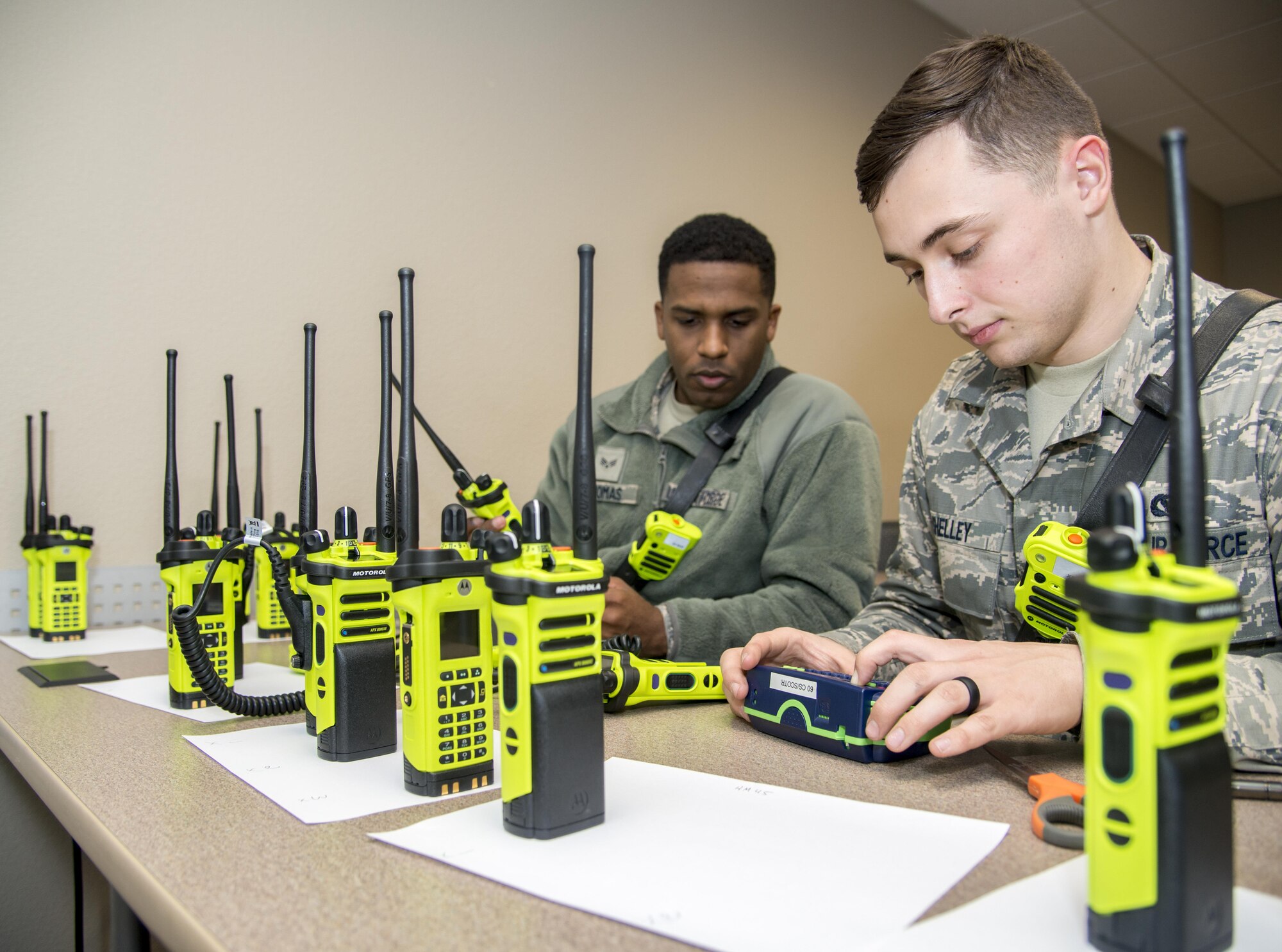 Airman 1st Class Nicholas Shelley, 60th Civil Engineer Squadron, right, and Senior Airman Danny Thomas, 60th Civil Engineer Squadron, program new radios received from the 60th Communications Squadron February 9, 2017 at Fire Station 1, Travis Air Force Base, California. The new radios allow the firefighters to seamlessly communicate with local fire departments, as well as those from Sacramento, Contra Costa, Napa, Vallejo and Cal Fire without having to change radios or carry multiple radios on themselves. (U.S. Air Force photo/Staff Sgt. Nicole Leidholm)