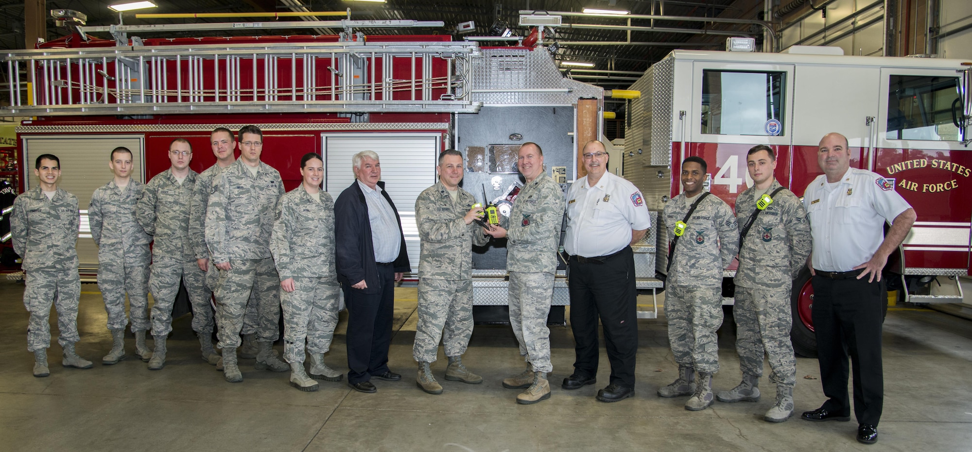 Lt. Col. Thomas Stady, 60th Communications Squadron commander, middle left, hands new radios over to Lt. Col. James Duke, 60th Civil Engineer Squadron commander, middle right, at Fire Station 1 Feb. 9, 2017 at Travis Air Force Base, California. The new radios allow the firefighters to seamlessly communicate with local fire departments, as well as those from Sacramento, Contra Costa, Napa, Vallejo and Cal Fire without having to change radios and carry multiple radios on themselves. (U.S. Air Force photo/Staff Sgt. Nicole Leidholm)